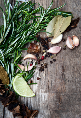 Herbs and spices on wooden background. Rosemary, lime and chili pepper, garlic and dry mushrooms.の写真素材