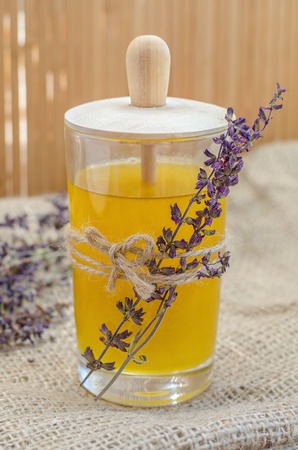 Honey in glass jar decorated with sprigs of dried lavender.の写真素材