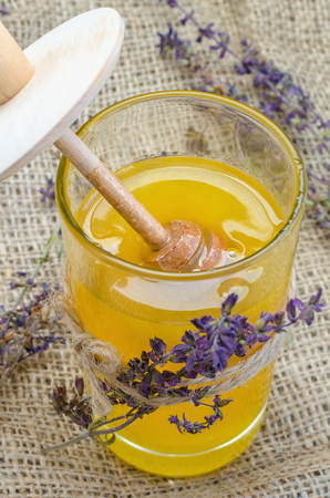 Honey in glass jar decorated with sprigs of dried lavender.の写真素材