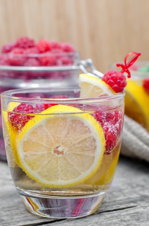 Glass of sparkling water with lemon and raspberry.の写真素材