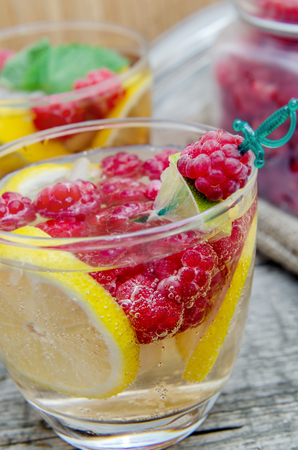 Glass of sparkling water with lemon and raspberry.の写真素材