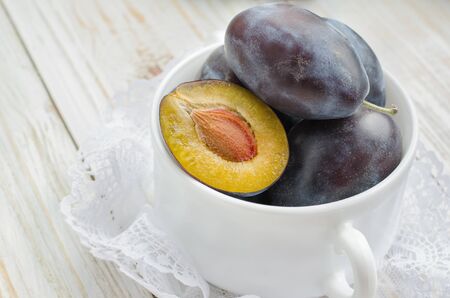 Fresh plums in white bowl on light background.の写真素材
