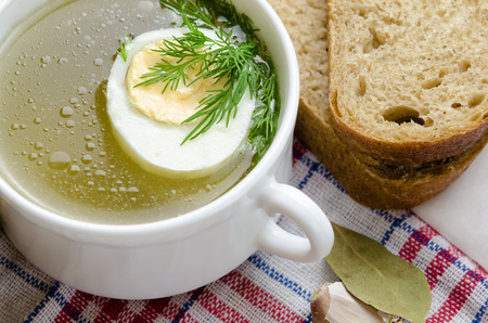 Chicken bouillon with egg and dill in the white bowl.の写真素材