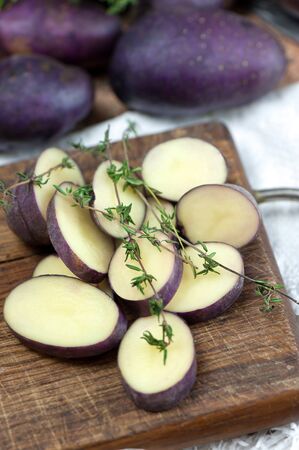 Raw sliced potato on wooden board. Thyme seasoning.の写真素材
