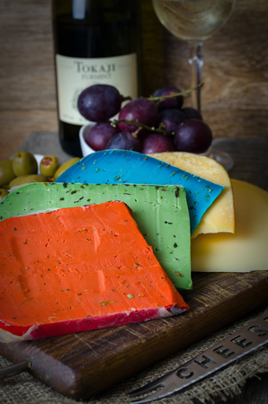 Colorful cheese mix and grapes on wooden background.