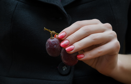 Pink manicure. Female hands with sparkle nail design holding grape.の写真素材