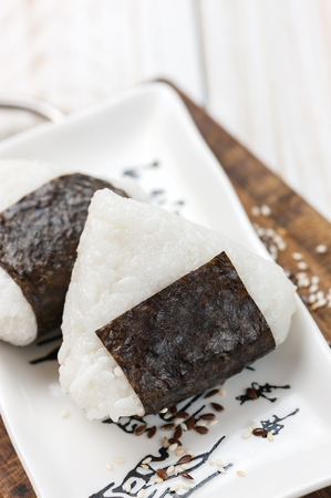Onigiri. Rice triangle with nori seaweed on white plate.の写真素材
