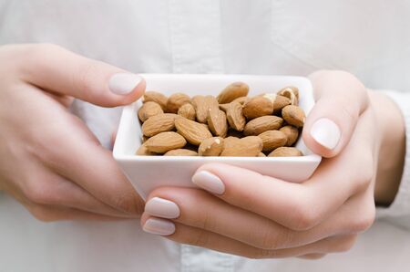 Almonds in white bowl on woman hands.の写真素材