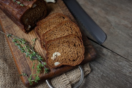 Sliced black bread with bacon on dark wooden background.