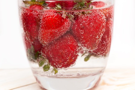 Glass of sparkling mineral water with strawberry.の写真素材