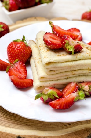 Freshly thin pancakes with strawberries on white plate.の写真素材