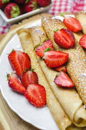Freshly thin pancakes with strawberries on white plate.の写真素材