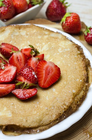 Freshly thin pancakes with strawberries on white plate.の写真素材
