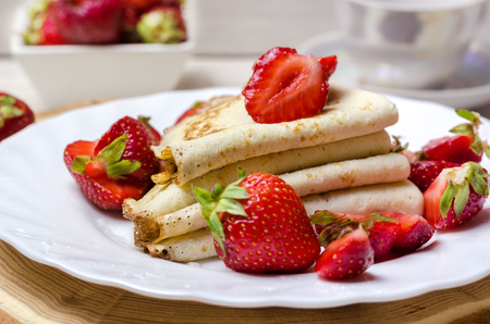 Freshly thin pancakes with strawberries on white plate.の写真素材