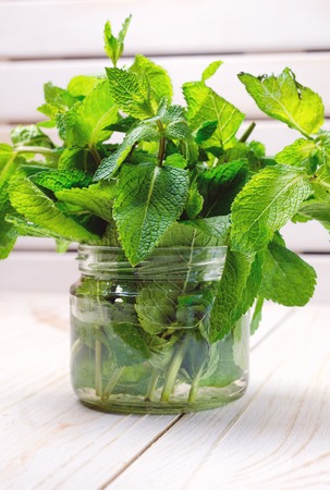 Fresh mint leaves in glass jar on white wooden background. Close up.の写真素材