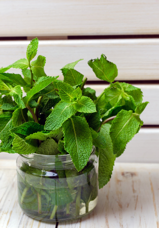 Fresh mint leaves in glass jar on wooden background.の写真素材