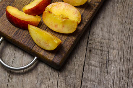 Sliced nectarine on dark wooden cutting board.の写真素材