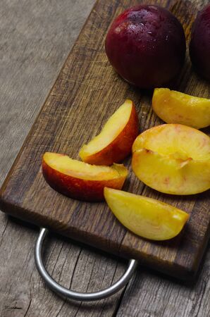 Sliced nectarine on dark wooden cutting board.の写真素材