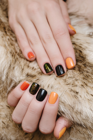 Beautiful female hand with orange and black nail art.の写真素材