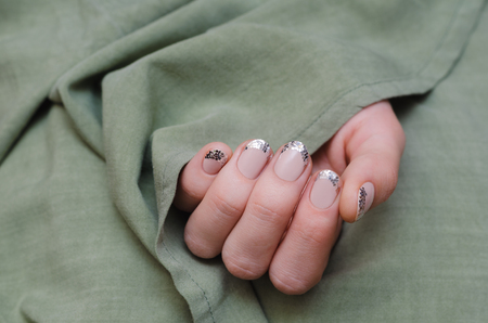 Beautiful female hand with glitter french manicure on green background.の写真素材