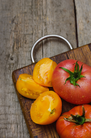 Delicious red and yellow tomatoes on wooden cutting board.の写真素材