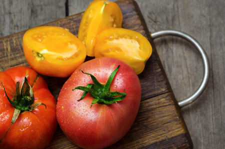 Delicious red and yellow tomatoes on wooden cutting board.の写真素材