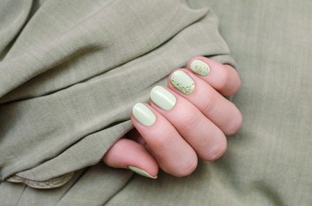 Beautiful female hand with lgreen nail art with gold mica.の写真素材