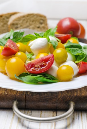 Salad with fresh mozzarella, tomatoes and basil in white plate.の写真素材