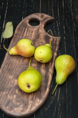 Fresh green pears on brown wooden cutting board.の写真素材