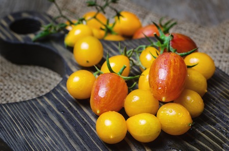 Yellow and red cherry tomatoes on wooden cutting board. Close up.の写真素材