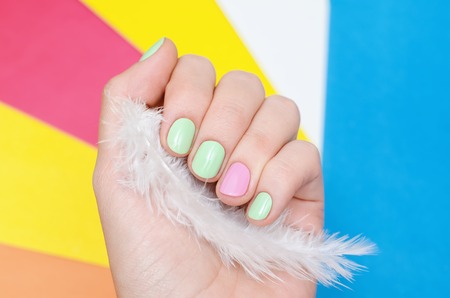 Beautiful female hand with light green and pink nail design on colourful background.の写真素材