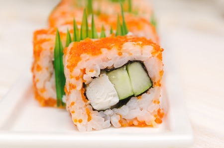 Homemade sushi roll with crab stick and cucumber on white plateの写真素材