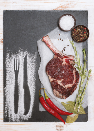 Raw beef steaks with bone on wooden board prepared for grill.の写真素材
