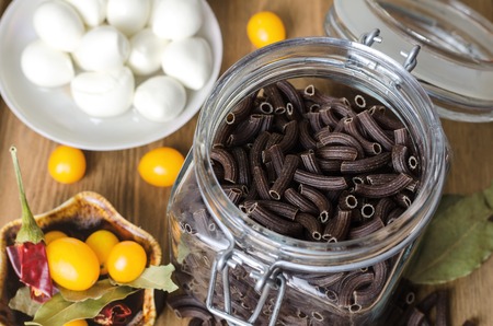 Raw black pasta in glass jar prepared for cooking.の写真素材
