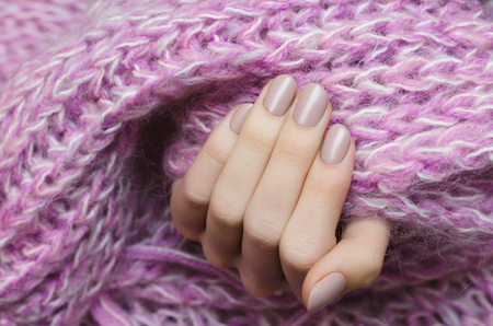 Beautiful female hand with beige manicure holding pink scarf.の写真素材