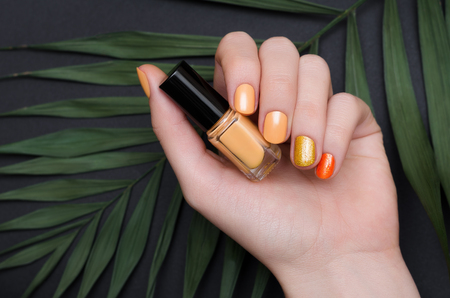 Beautiful female hand with yellow nail design with gold glitter.の写真素材