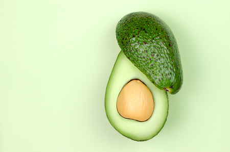Fresh green avocado on light green background.