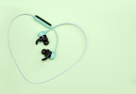 Green wireless headphones on light green background.