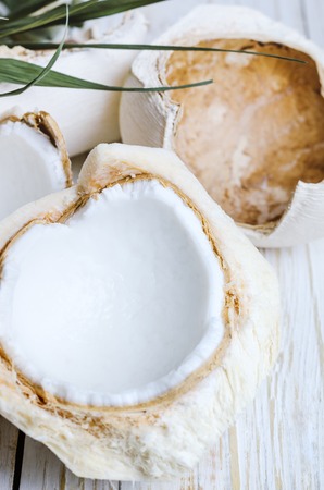 Open young coconut on white wooden background.の写真素材