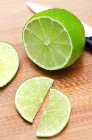 Juicy slice of lime on wooden cutting board.の写真素材