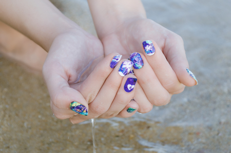Female hands with purple nail art stickers.の写真素材