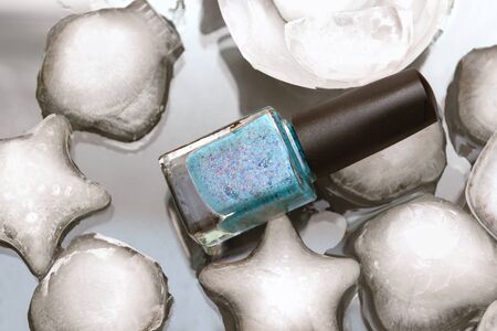 Nail polish bottle and ice with sea shells form.