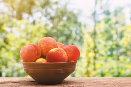 Ripe peaches in a bowl on wooden backgroundの写真素材
