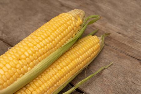 Fresh corn on cobs on wooden background