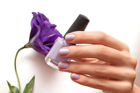 Female hand with glitter nail design holding nail polish bottleの写真素材