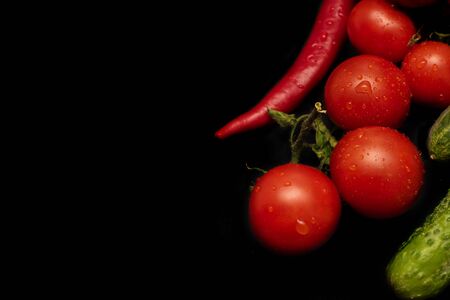 Ripe tomatoes and cucumbers on black backgroundの写真素材