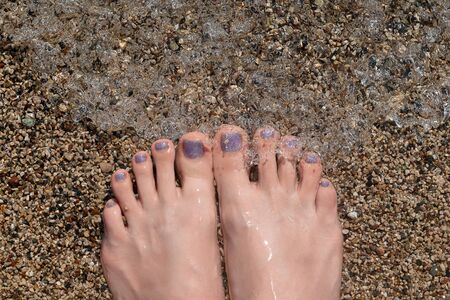 Female feet with glitter pedicure under clear waterの写真素材
