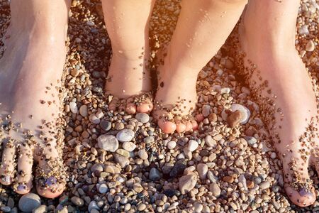 Baby and mother feet on the sea pebbles on sunlight.の写真素材
