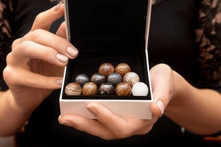 Sets of round stones in female hands on black background.の写真素材