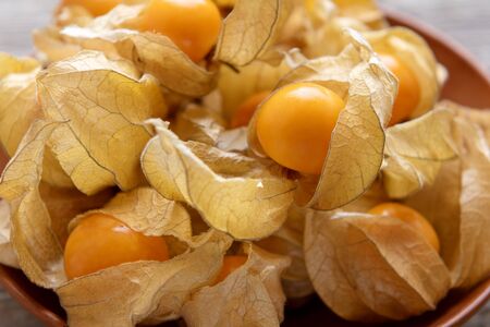 Ripe yellow physalis on wooden background, close up
